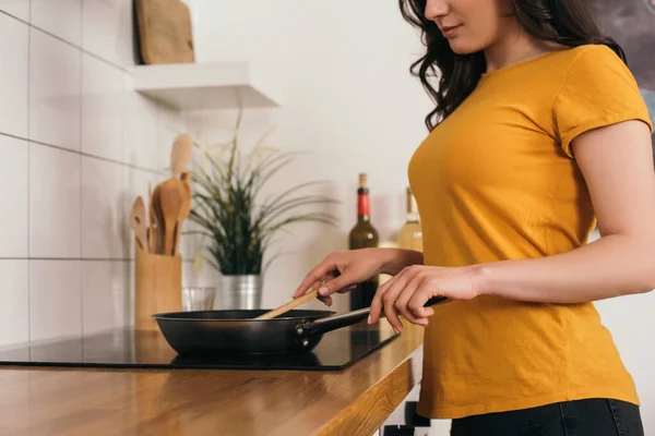 Cropped view of woman holding wooden spatula near frying pan — Stock Photo