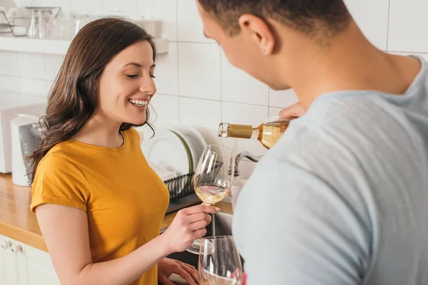Selective focus of bi-racial man holding bottle of wine near glasses and smiling girlfriend — Stock Photo
