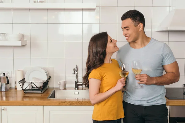 Glückliches gemischtrassiges Paar, das zu Hause Gläser mit Weißwein hält — Stockfoto