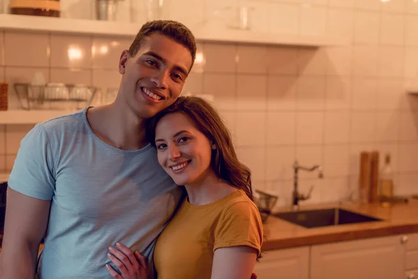 Feliz casal multirracial sorrindo enquanto abraça em casa — Fotografia de Stock