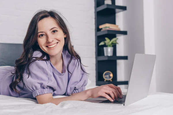 Freelancer alegre e atraente usando laptop na cama — Fotografia de Stock