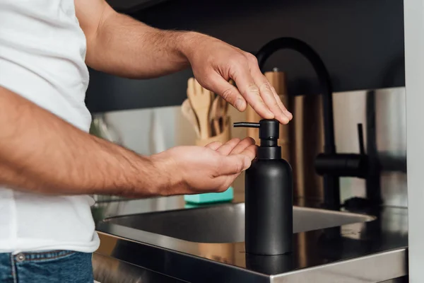 Vista cortada do homem tocando dispensador de sabão na cozinha — Fotografia de Stock