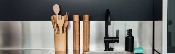 Conceito panorâmico de moinho de pimenta de madeira e moinho de sal perto da torneira, pia, dispensador de sabão e esponja na cozinha — Fotografia de Stock