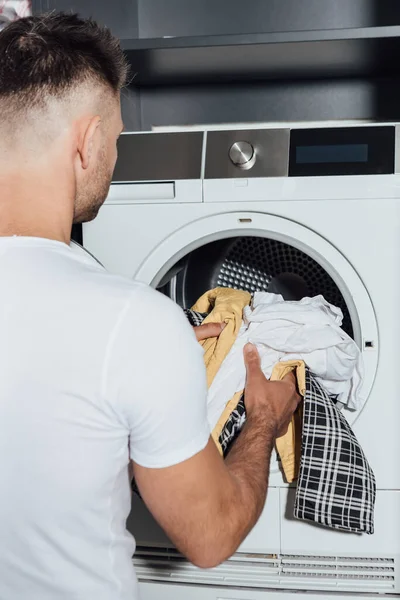 Человек кладет грязное белье в современную стиральную машину — стоковое фото