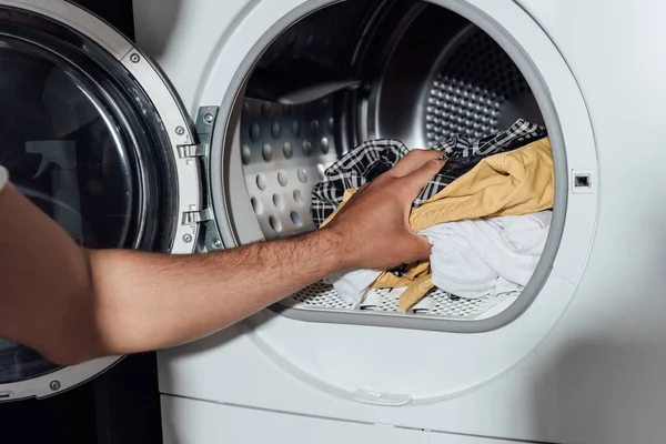 Vista cortada do homem colocando roupa suja na máquina de lavar roupa — Fotografia de Stock