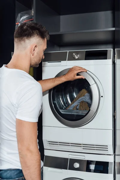 Handsome man touching modern washing machine — Stock Photo