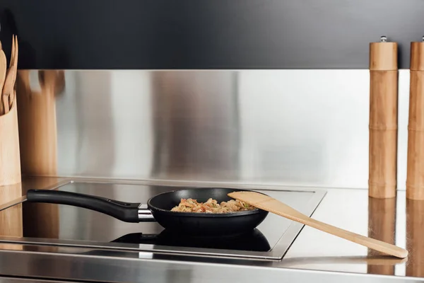 Spatula near frying pan with noodles on stove in kitchen — Stock Photo