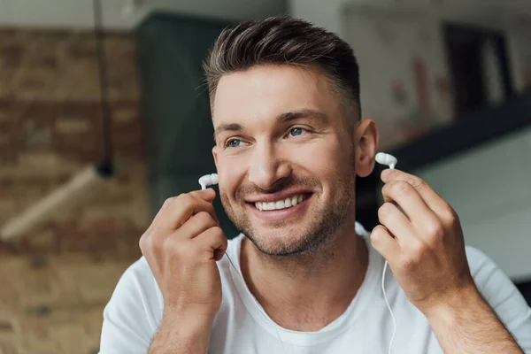 Hombre sonriente sosteniendo auriculares en la sala de estar - foto de stock