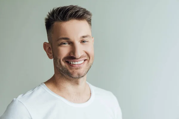 Handsome man smiling while looking at camera isolated on grey — Stock Photo