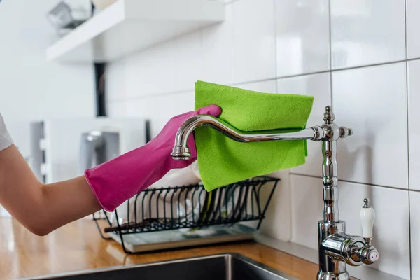 Cropped view of woman in rubber glove holding rag near faucet — Stock Photo