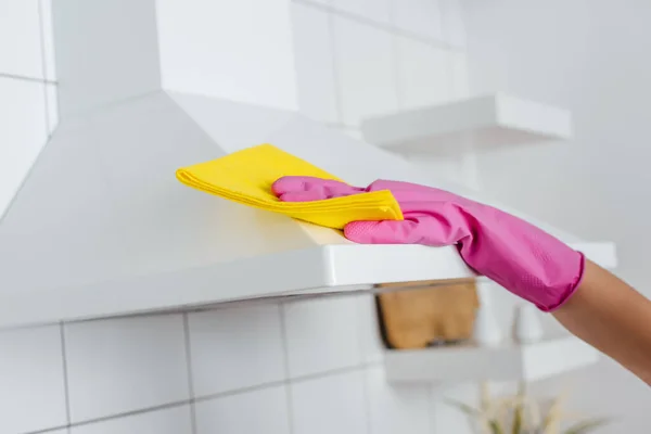 Vista recortada de la mujer en guante de goma rosa limpieza campana de la cocina - foto de stock