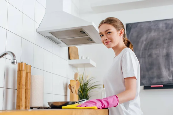 Enfoque selectivo de la mujer alegre en guante de goma rosa limpieza cocina - foto de stock