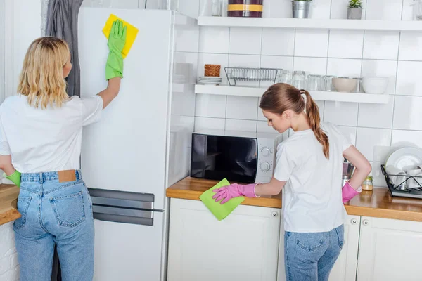 Schwestern in Gummihandschuhen halten Lumpen beim Putzen der Küche — Stockfoto