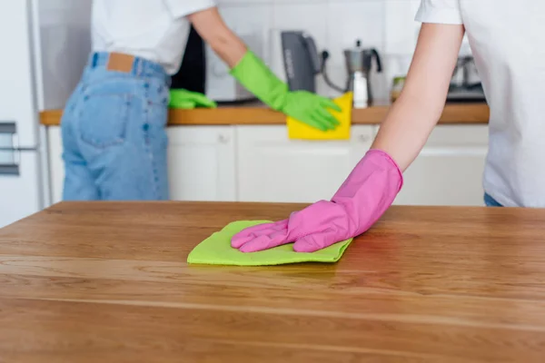 Vue recadrée de sœurs en gants de caoutchouc nettoyage cuisine — Photo de stock