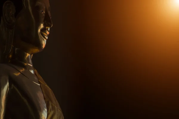 Portrait of a golden Buddha statue in the dark rooms with sunlig — Stock fotografie