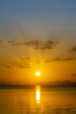 Gölde bulutlu günbatımının dikey görüntüsü.