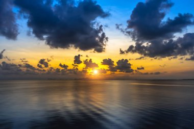 Güneş batarken gökyüzünde gölde, siluet dağında ve bulutlarda.