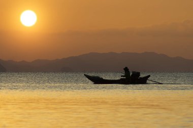 balıkçı teknesi güneş ışığı ile gölde silüeti.