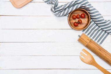 Cherry tomatoes with wooden spatula and salt grinder with table cloth on tabletop clipart