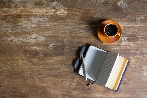 top view of diary with pencil and coffee cup on wooden tabletop 