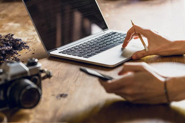 Pessoa usando laptop e smartphone no espaço de trabalho com câmera fotográfica vintage — Fotografia de Stock