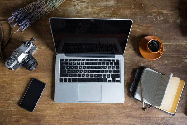 Vue de dessus de l'ordinateur portable, journal, appareil photo vintage et tasse de café sur table en bois — Photo