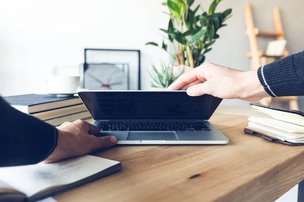 Mänskliga händer hålla laptop på arbetsplatsen i hemmakontoret — Stockfoto