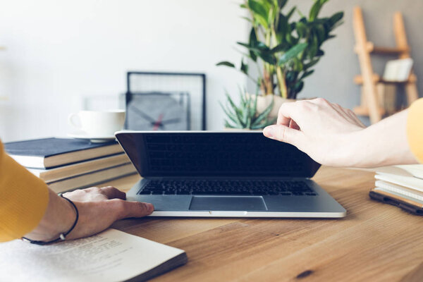 human hands holding laptop at workplace in home office