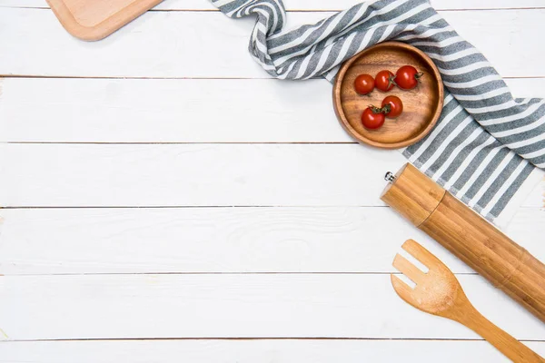 Cherry tomatoes with wooden spatula and salt grinder with table cloth on tabletop — Stock Photo, Image