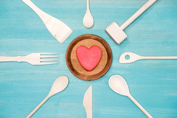 Вид сверху на различные деревянные кухонные принадлежности с символом сердца на тарелке — стоковое фото