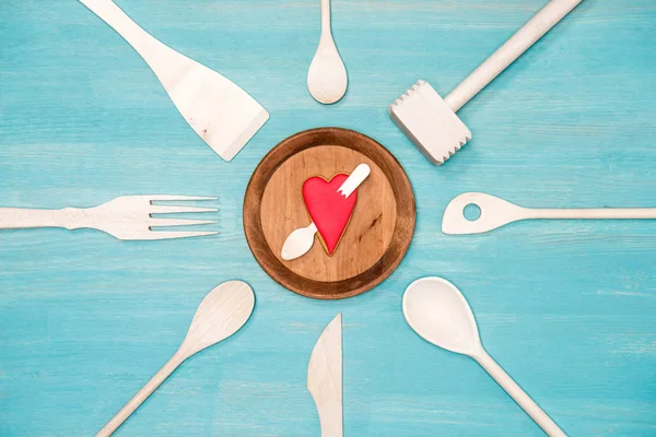 Top view of various wooden kitchen utensils with pierced heart symbol on plate — Stock Photo, Image