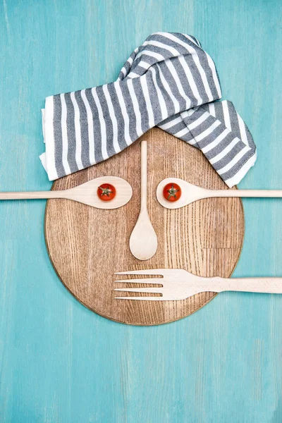Вид зверху дерев'яного посуду для приготування їжі з помідорами у вигляді обличчя на кухонній дошці — стокове фото