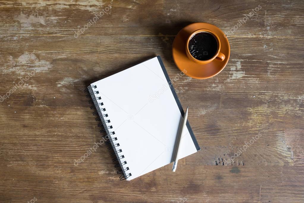 top view of notepad with pencil and coffee cup on wooden tabletop 