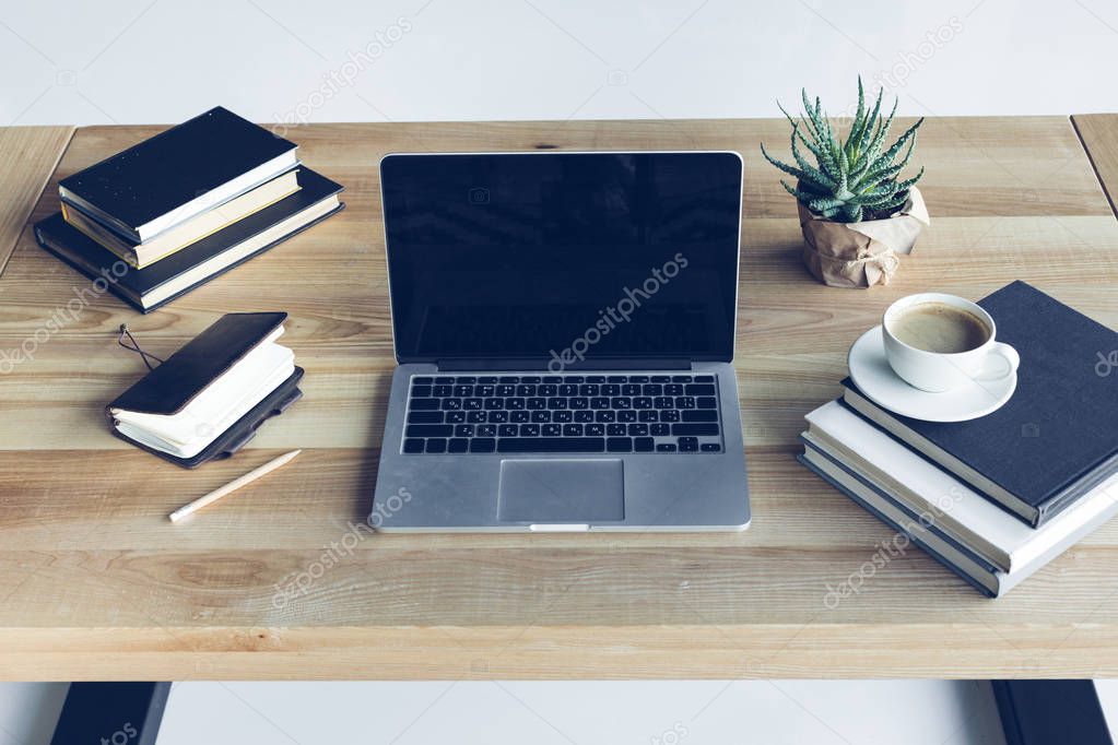 Close-up view of open laptop with blank screen and cup of coffee at workplace  