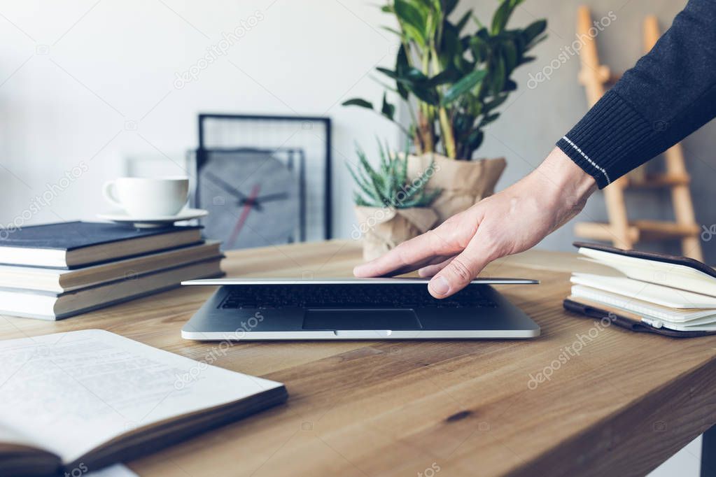 human hand holding laptop at workplace in home office