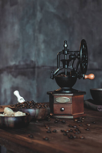 старинная кофемолка с фасолью на столе
