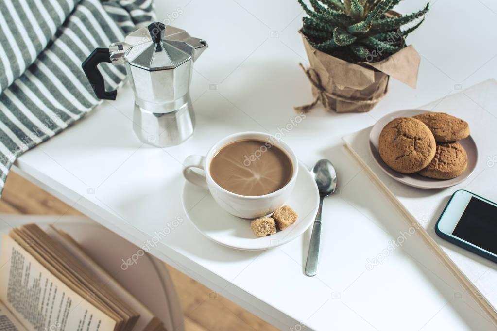 coffee with cookies and potted plant on tabletop