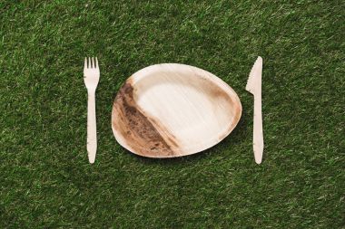 wooden plate with fork and knife on grass clipart