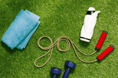 towel and bottle with jump rope on grass clipart