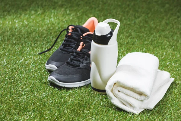 Trainers with bottle of water and towel on pitch — Stock Photo, Image