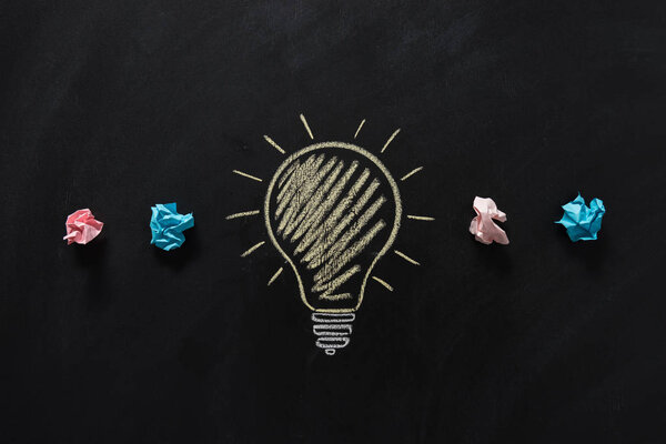 бумажный мусор с электрической лампочкой на доске
