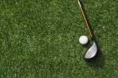 golfovou hůl a míček na trávě