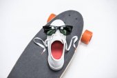 Turnschuh und Sonnenbrille auf Skateboard