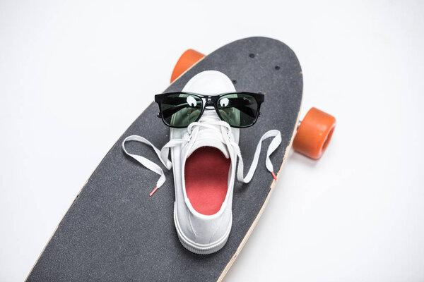 кроссовки и солнечные очки на скейтборде
