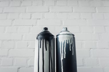 close up view of spray paint in cans with brick wall background clipart