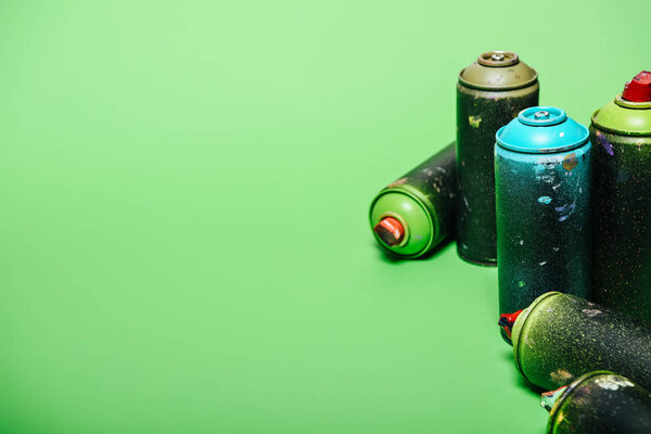 close up view of arranged cans with aerosol paint isolated on green