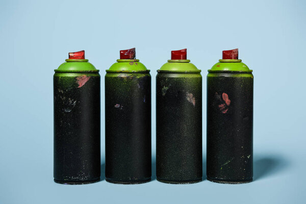 close up view of arranged cans with aerosol paint isolated on blue