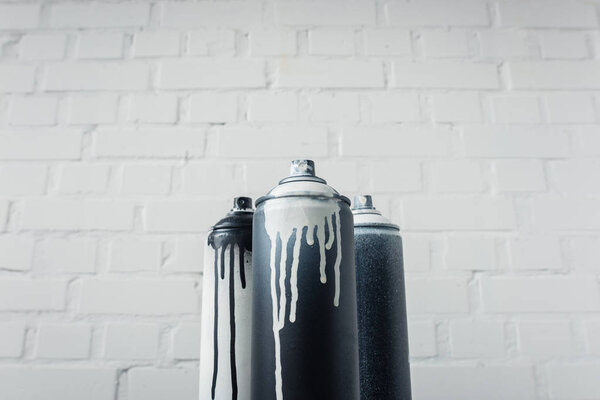close up view of spray paint in cans with brick wall background