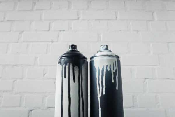 close up view of spray paint in cans with brick wall background