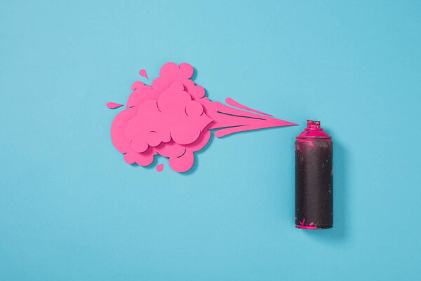 top view of spray paint in can and paper splashes isolated on blue